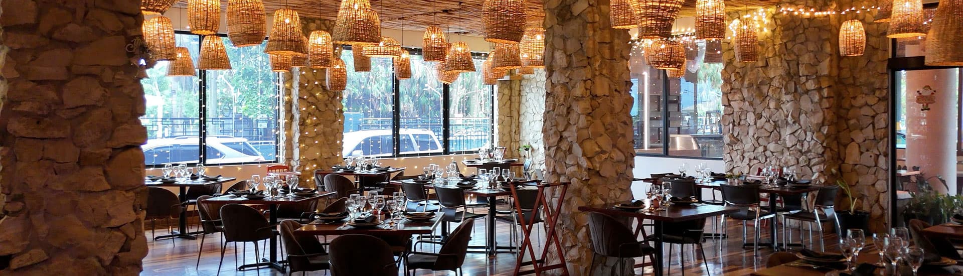 A stylish restaurant interior featuring stone walls, wooden tables, and artisan hanging lights.