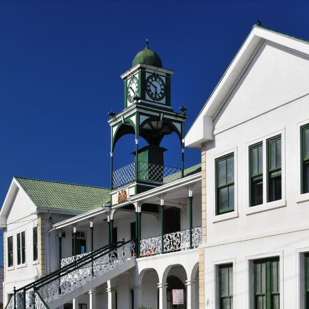 Historic building with a green and white clock tower under a clear blue sky.