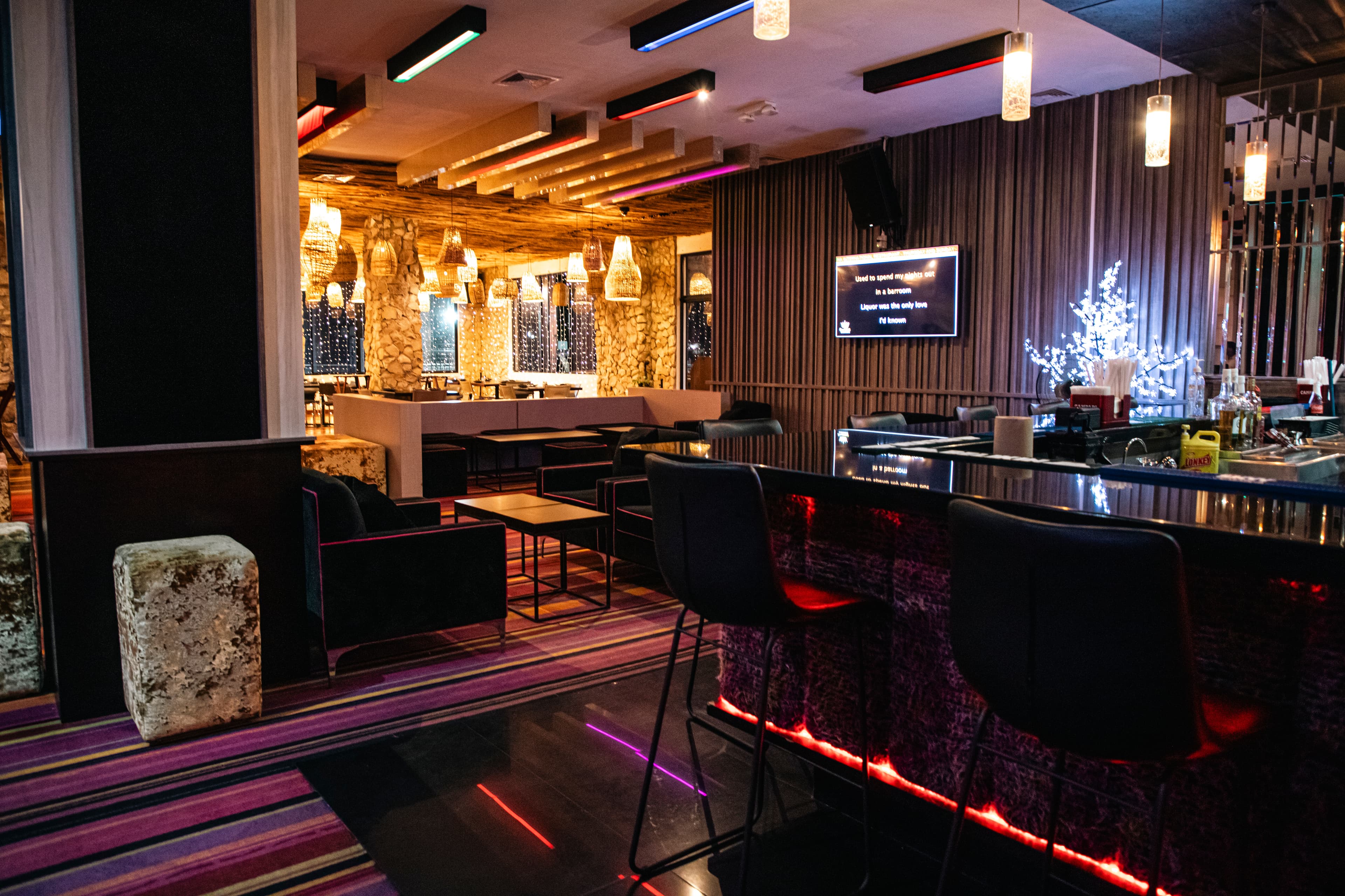 Interior of a stylish bar featuring modern seating, colorful lighting, and a contemporary design.